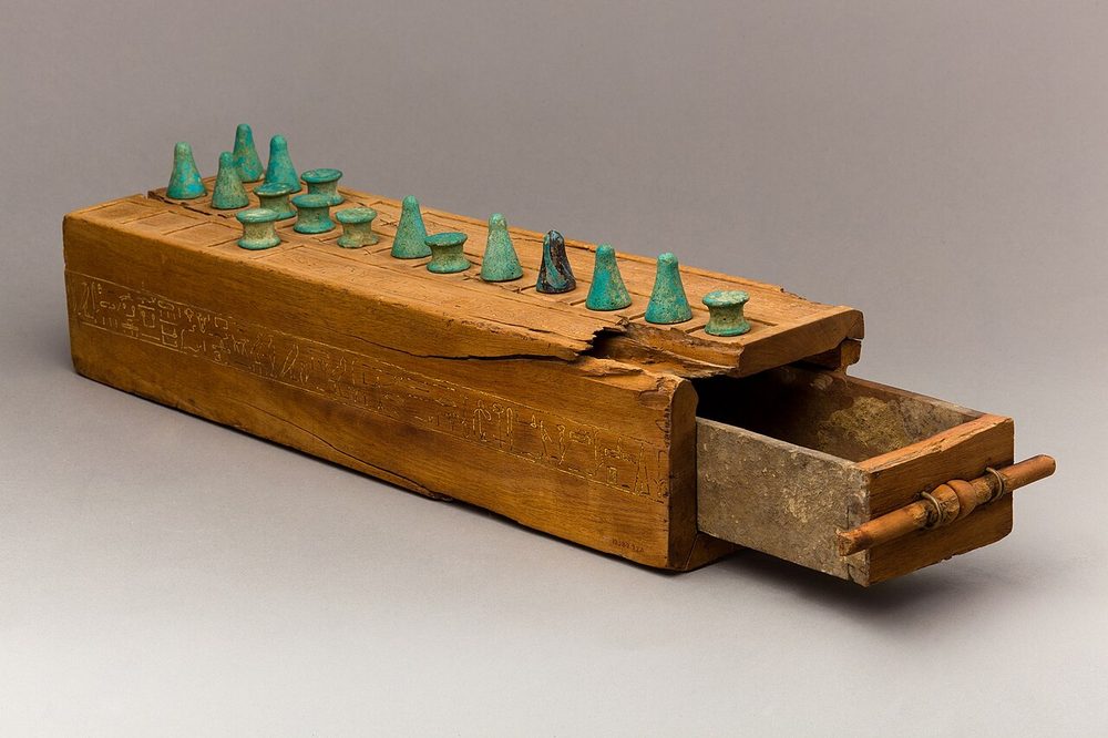 An ancient Egyptian wooden game box with gaming pieces on top